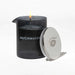 Eye of Love Matchmaker black glass massage candle with lit wick and silver lid on white background