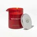 Red glass Eye of Love Matchmaker pheromone massage candle with a silver lid beside it on a white background.