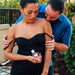 Couple sharing an intimate moment outdoors with woman holding Eye of Love Pheromone Parfum bottle in black dress.