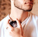 Man applying Eye of Love Matchmaker Pheromone Perfume Black Diamond cologne from a stylish glass bottle.