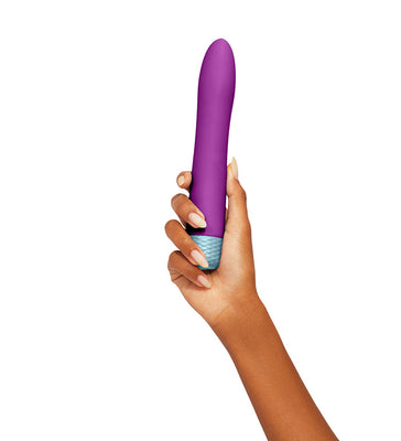 Hand holding a purple Femme Funn Densa Flexible Bullet with textured blue base against white background.