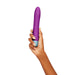 Hand holding a purple Femme Funn Densa Flexible Bullet with textured blue base against white background.