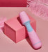 Compact pink and blue Femme Funn Ffix Mini Wand vibrator displayed on a pink box with soft pink feathers nearby.
