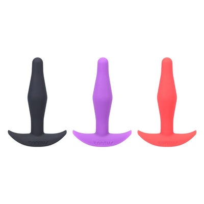Three Tantus Little Flirt butt plugs in black, purple, and coral, standing upright on a white background.