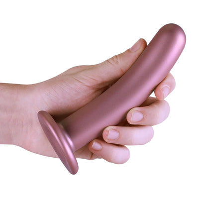Hand holding a smooth, rose gold 6-inch silicone G-spot dildo with a strong suction cup base.