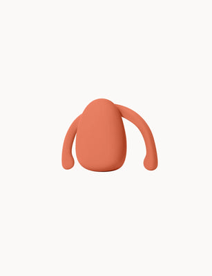 Compact hands-free wearable vibrator in terracotta color with flexible arms for secure, comfortable fit.