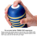 Hand holding a blue and gold striped Tenga Premium Original Vacuum Cup with a finger covering the air hole on top.