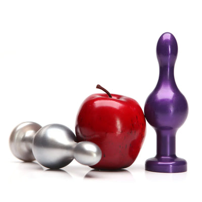 Two metallic joystick-shaped adult toys in silver and purple next to a red apple for size comparison on a white background.