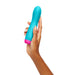 Hand holding a blue and pink rechargeable silicone rotating bullet vibrator with a smooth, curved design.