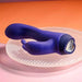 Purple silicone dual stimulator vibrator with ergonomic curves and a crystal-like decorative base on a textured round platform.