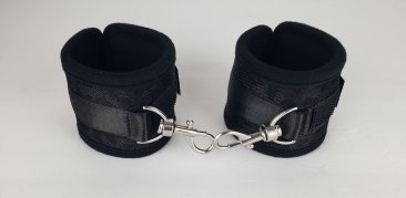 Pair of black neoprene wrist restraints with adjustable straps and metal lobster clasp connection.