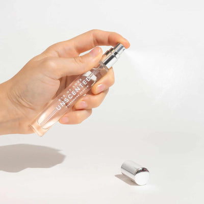 Hand holding Eye of Love Unscented Pheromone Perfume spray bottle with silver cap on white background