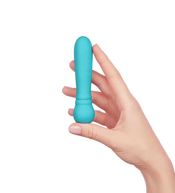 Hand holding a compact turquoise silicone mini massager with a rounded tip and ergonomic base.