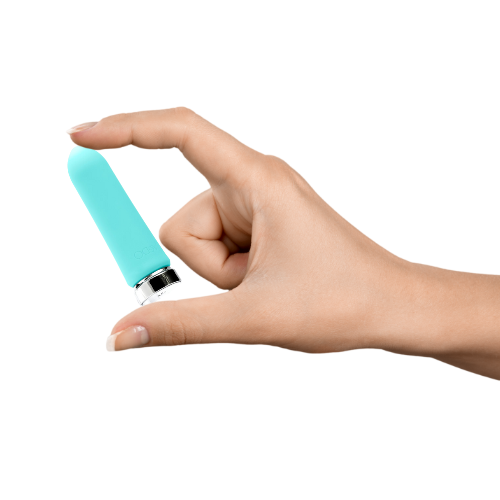 Hand holding a compact turquoise rechargeable silicone bullet vibrator with silver base against white background.