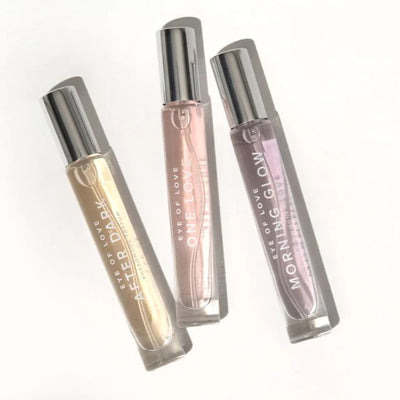 Set of three Eye of Love pheromone perfumes in sleek glass roller bottles with silver caps, labeled After Dark, One Love, and Morning Glow.