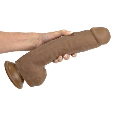 Hand holding a large brown realistic dildo with suction cup base against a white background.