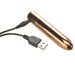 Sleek copper-colored rechargeable bullet vibrator with USB charging cable connected on white background.