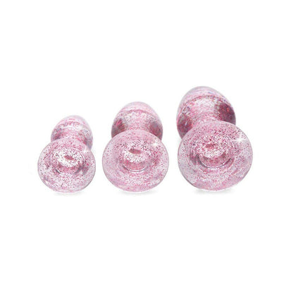 Set of three pink glittery acrylic butt plugs in small, medium, and large sizes with gem-shaped bases on white background.