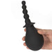 Hand holding a black silicone douche with a textured nozzle and bulb-shaped base for easy grip.