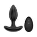 Black vibrating silicone anal plug with textured shaft and curved base next to a wireless remote control with two buttons.