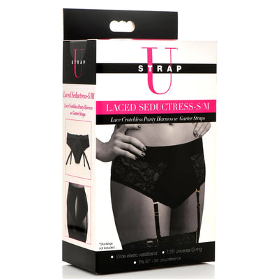 Packaging for a black lace crotchless panty harness with garter straps, shown worn with stockings on a model.