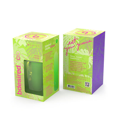 Packaging of B Swish Bdesired Infinite Deluxe Limited Edition vibrator in vibrant green with tropical leaf design and pink accents.