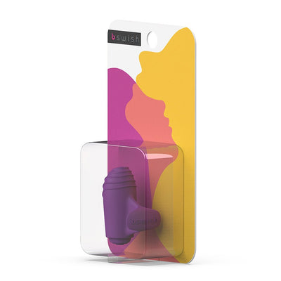 Purple B Swish Bteased Basic mini massager with textured ridges in clear plastic packaging on colorful abstract background.