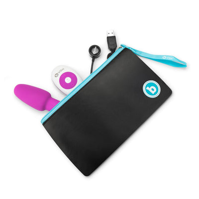 Purple B-Vibe Rimming Petite Plug with white remote, USB charger, and black storage pouch with blue zipper and wrist strap.