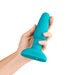 Hand holding a teal silicone B-Vibe Rimming Plug 2 with a tapered shape and wide base on a white background.