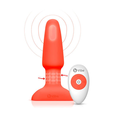 Red silicone B-Vibe Rimming Plug 2 with rotating beads and white wireless remote control on white background.