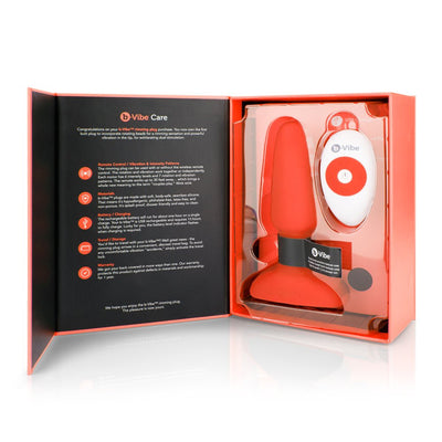 Open box packaging of B-Vibe Rimming Plug 2 in red with wireless remote control and care instructions inside.