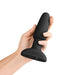 Hand holding a black silicone B-Vibe Rimming Plug 2 with a flared base and smooth, curved design.