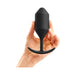Hand holding a black silicone weighted plug with a smooth grip handle and tapered tip.