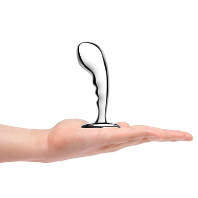 Hand holding a polished stainless steel prostate plug with a curved, ergonomic design and textured grip.