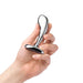 Hand holding a polished stainless steel prostate plug with a curved, ridged design and wide base.