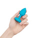 Hand holding a small blue silicone vibrating jewel plug with a tapered tip and flat base.
