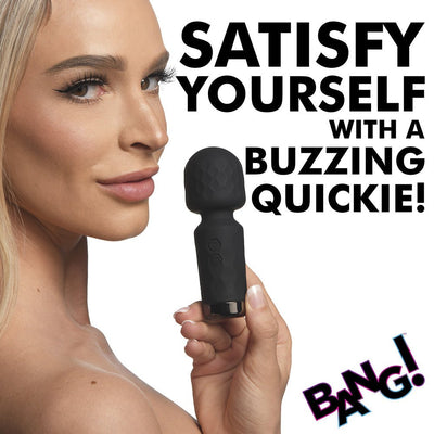 Woman holding a black mini silicone wand vibrator with textured head and control buttons against a white background.