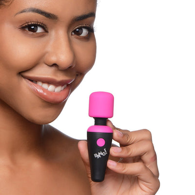 Smiling woman holding a compact pink and black BANG! 10X Vibrating Mini Wand with flexible neck and single button.
