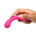 Hand holding a bright pink, curved silicone G-spot vibrator with a rounded, ribbed head and control buttons.