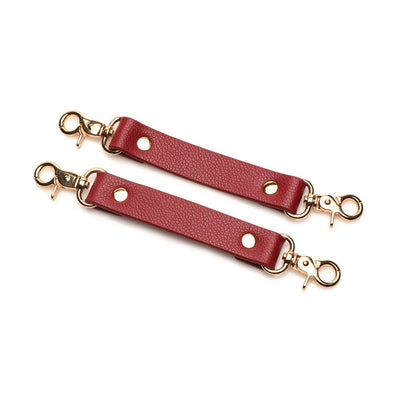Red vegan leather cuff connectors with gold-tone metal clasps for adjustable restraint sets.
