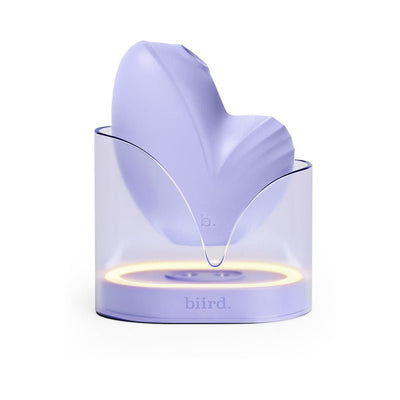 Biird Namii clitoral stimulator in lavender with a translucent charging base featuring a soft ambient light ring.