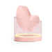 Biird Namii clitoral stimulator in soft pink silicone resting in a translucent charging base with ambient light ring.
