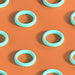 Pattern of mint-colored silicone C-rings with textured details on an orange background.