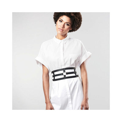 Woman wearing a white shirt dress styled with a black vegan leather Maze wide belt restraint around the waist.