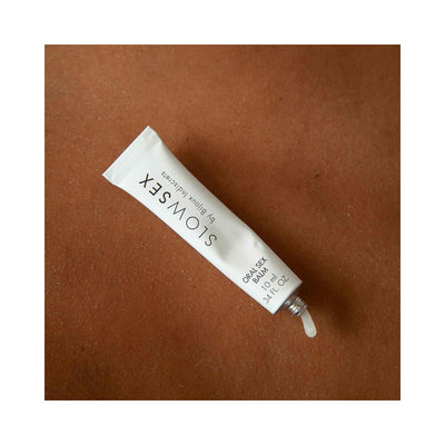 Tube of Bijoux Indiscrets Slow Sex Oral Sex Balm with a small amount of balm on a brown textured surface.