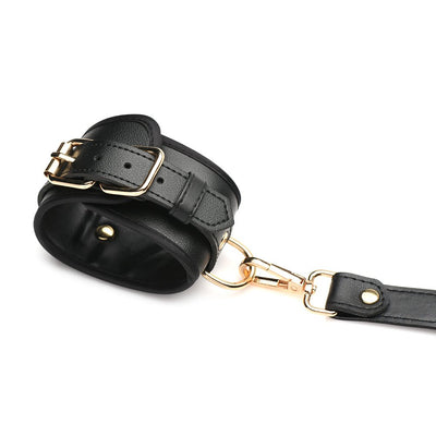 Black PU leather wrist cuff with gold buckle and clasp detail on white background