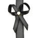 Close-up of black faux leather thigh harness strap with decorative bow and gold-tone rivet detail.