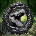 Black silicone cock ring shaped like a grinning caiman with textured ridges and bumps, set against a swamp background.