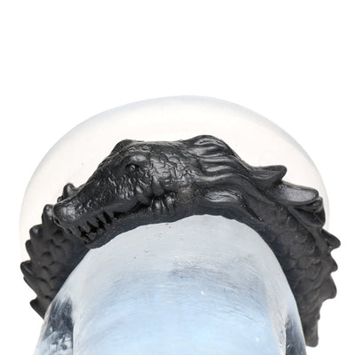 Black silicone cock ring shaped like a smiling caiman with textured ridges and scales, displayed on a clear model.