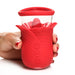 Hand holding a red silicone flower-shaped personal massager with three control buttons on the front.